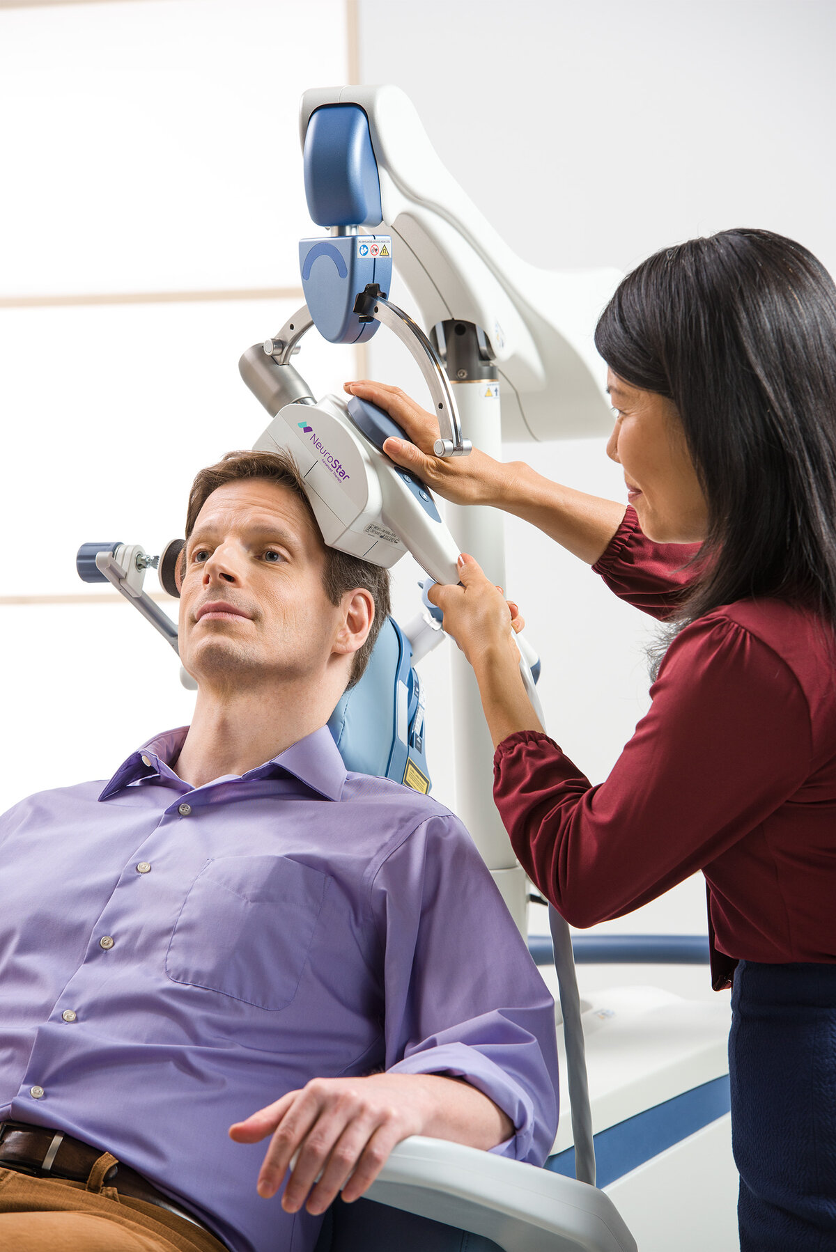 Clinician positioning a NeuroStar® coil on a male patient